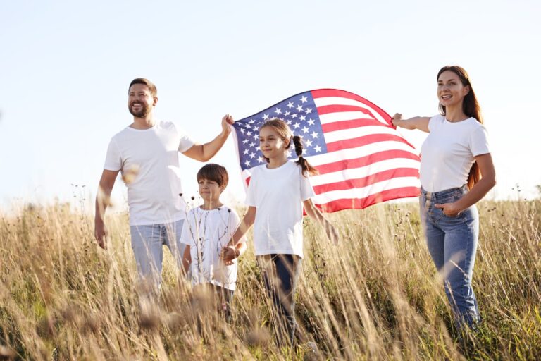 A family of four holding up an American flag