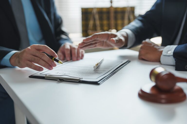 Two people going over paperwork on a clipboard on a desk