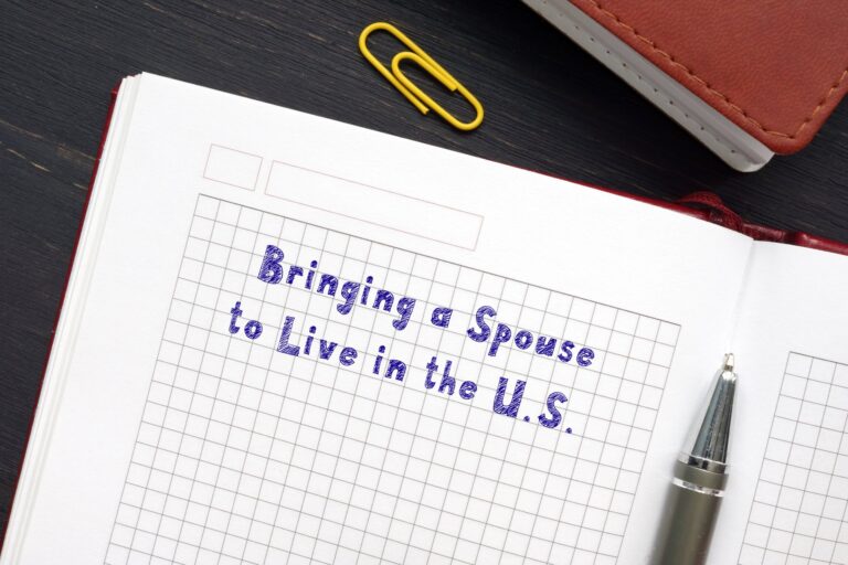 Yellow paperclip next to a paper that says bringing spouse to live in the u.s. with a black pen