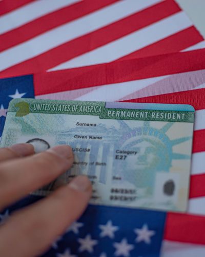 Permanent Resident Green card  of United states of America on flag of USA. Above close up view.